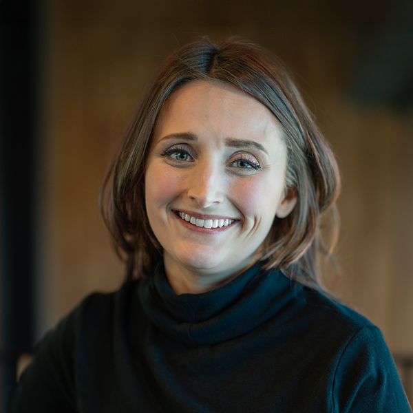 Hannah Dannewitz, Assistant Executive Director at Rock Creek Senior Living, smiling warmly indoors in professional attire with a softly lit wooden background.