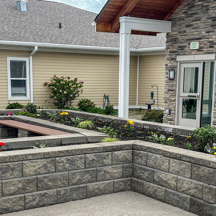 Raised stone flowerbeds at Rock Creek Senior Living, planted with colorful flowers.