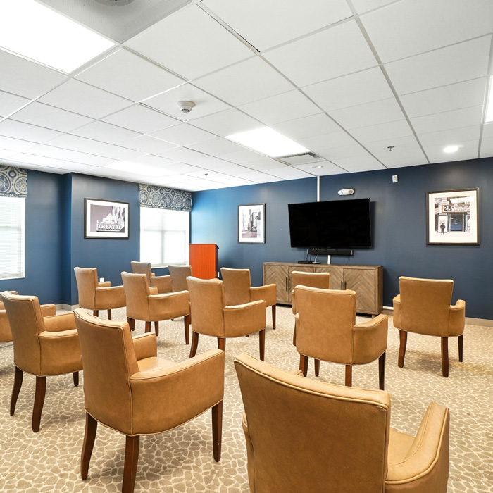 Community theater and gathering room with comfortable seating and large television for resident entertainment and events.