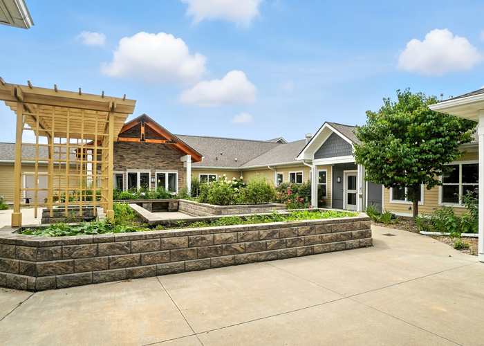 Outdoor courtyard with raised garden beds, walking paths, and landscaped gathering spaces at a senior living community.